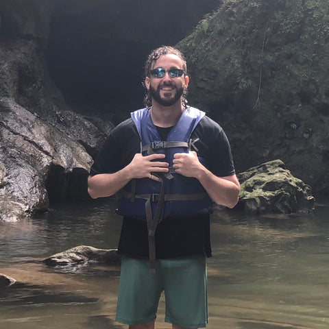 man in tropical river wearing metal wrap around sunglasses