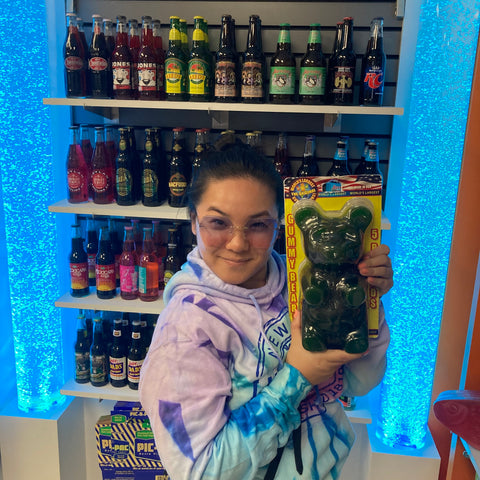 woman holding giant gummy bear while wearing rimless sunglasses