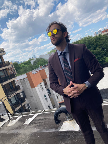 man on rooftop wearing maroon suit and mirrored round sunglasses