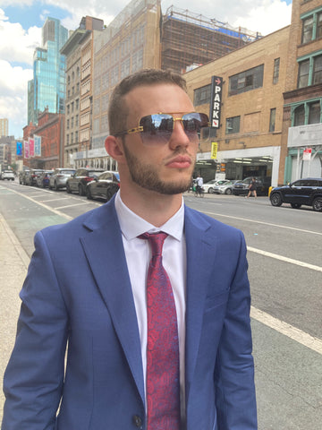 man wearing a suit and aviator sunglasses while standing on a NYC street