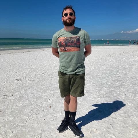 man on beach wearing round gold sunglasses