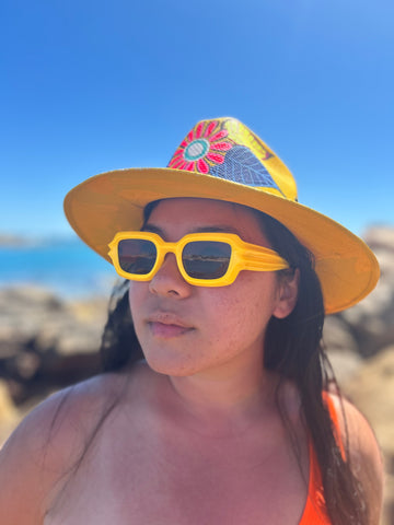 woman wearing bright yellow hat and yellow sunglasses on beach