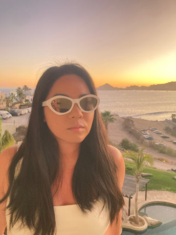 asian girl wearing white sunglasses in front of sunset