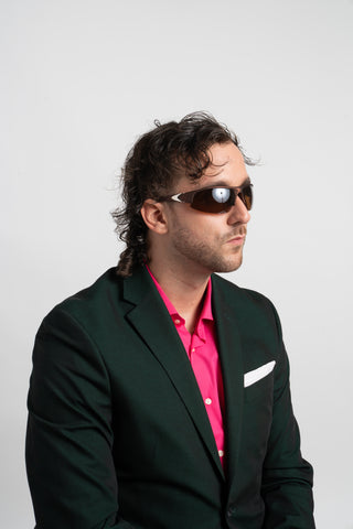 man in a green and pink suit wearing wrap around sunglasses
