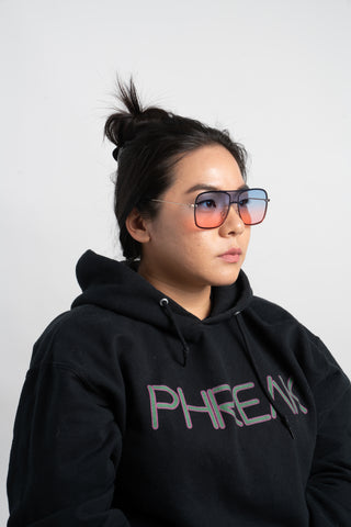 woman wearing black hoodie and pink blue and gold shield aviator sunglasses