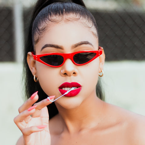 woman chewing gum wearing red skinny cat eye sunglasses