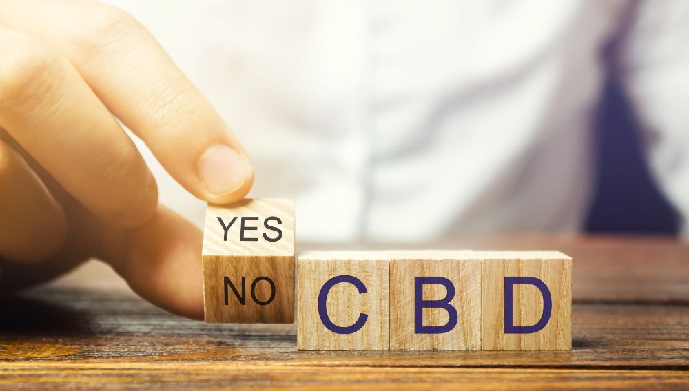 Cannabidiol, dados con las letras CBD con la mano de una persona intentando elegir entre sí o no