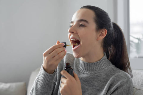 Mujer joven tomando gotas de CBD