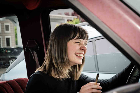 On the Road with CBD - A girl parked while smoking a hemp pre-roll 