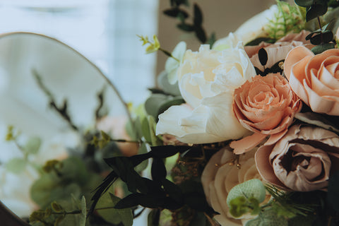 A blush and white sola wood flower bridal bouquet sets in front of a mirror.