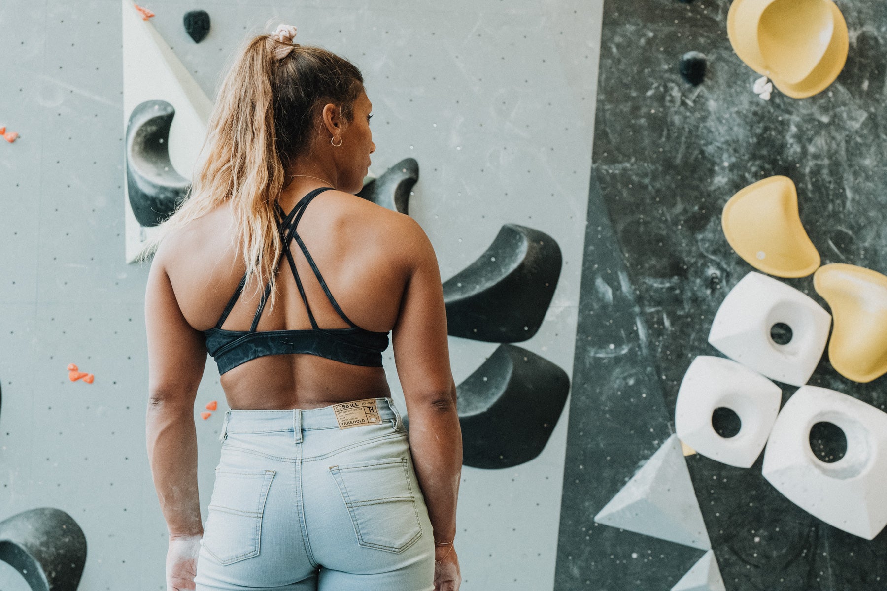 Meagan Martin climbing a bouldering problem at Climb so iLL in the So iLL x Meagan Martin light wash denim