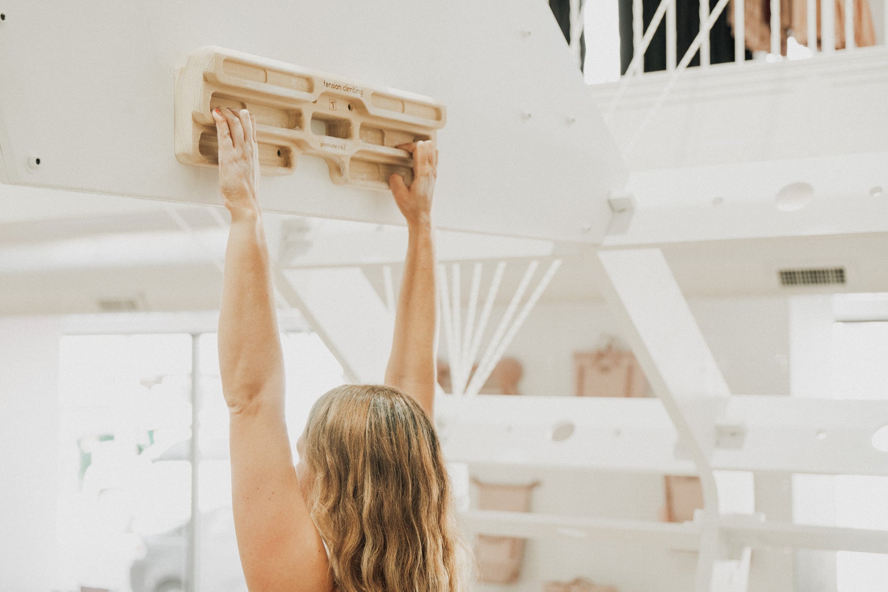 So iLL x Tension wooden trainers hanging from a pink rope with a person training from them