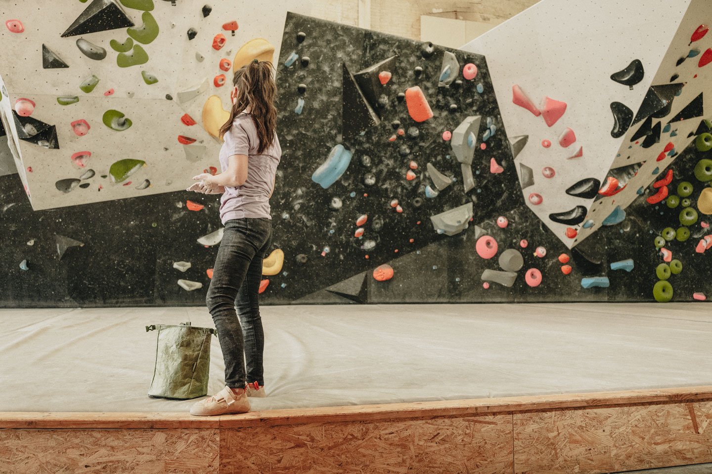 a woman gets ready to climb at climb so ill while using the eden green tyvek chalk bucket