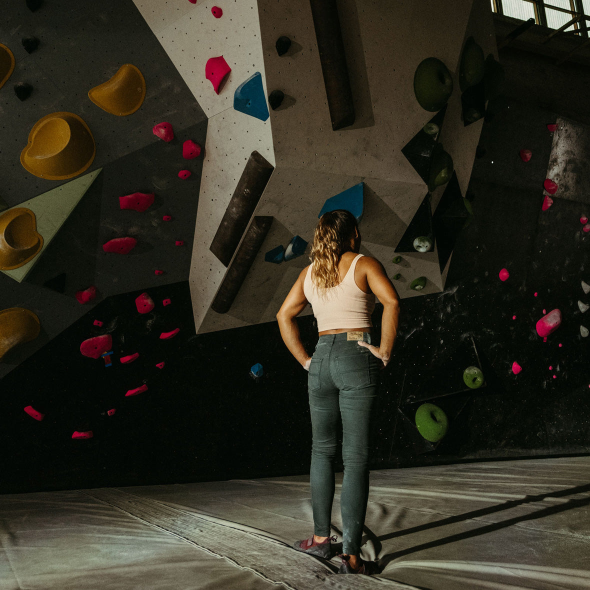 Meagan Martin looks at a climbing wall while wearing the so ill forest denim and new zero pro climbing shoes