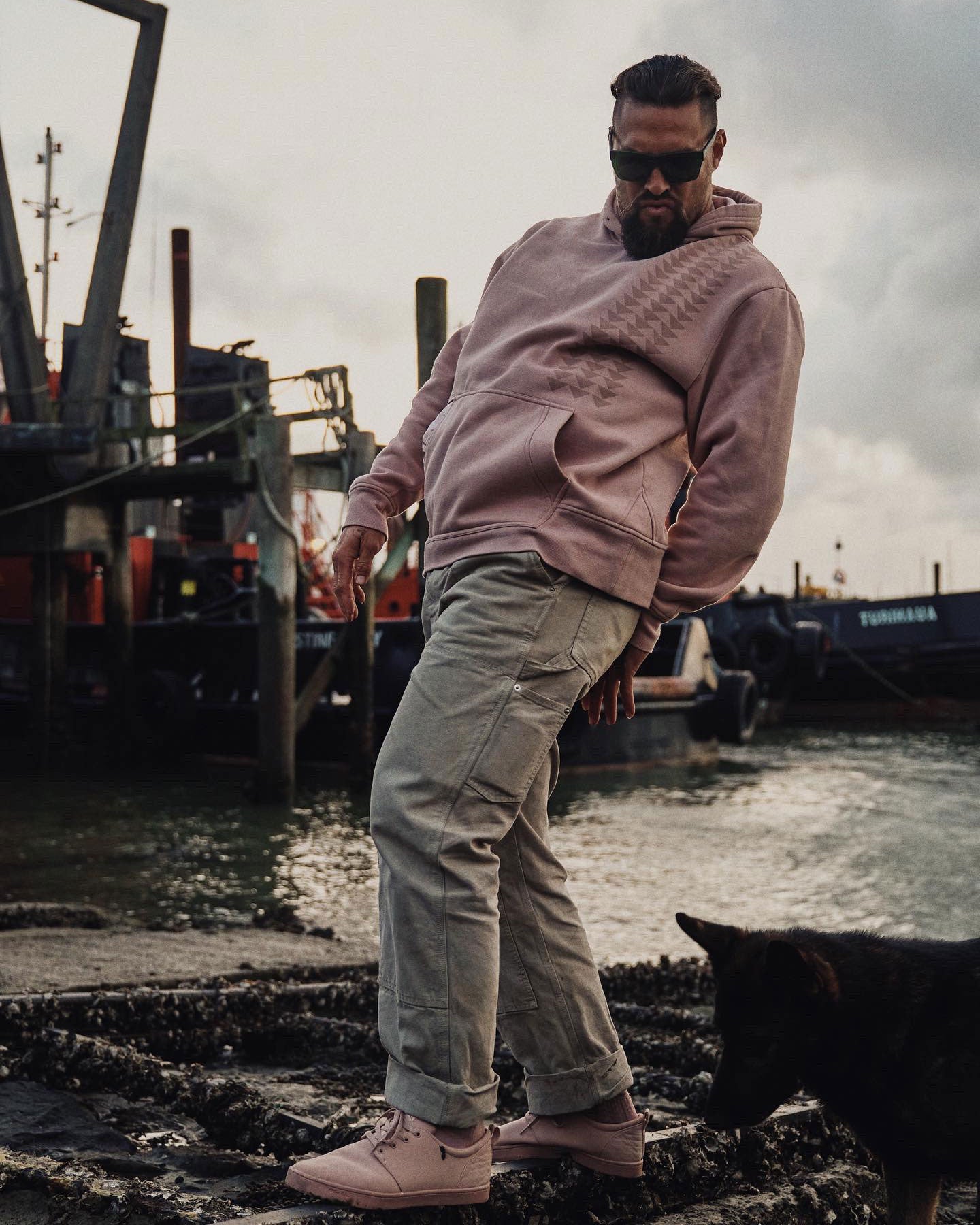 Jason Momoa wears the so ill x on the roam dirty pink nokoa hoodie while at a shipyard