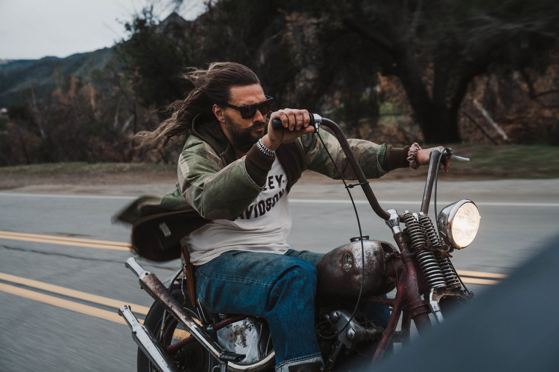 Jason momoa is shown in the matte rose tort electic sunglasses whilst riding a motorcycle