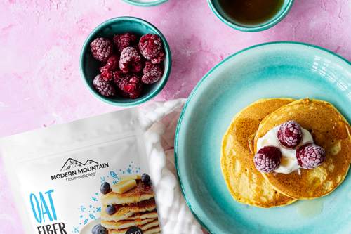 A pouch of Modern Mountain oat fiber next to pancakes with raspberries