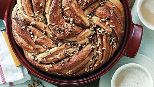 Cinnamon bun loaf in a red pan sprinkled with nuts