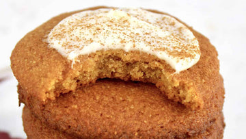 A half-eaten keto pumpkin cookie topped with frosting and spices