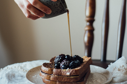 Syrup being poured over a stack of blueberry French toast