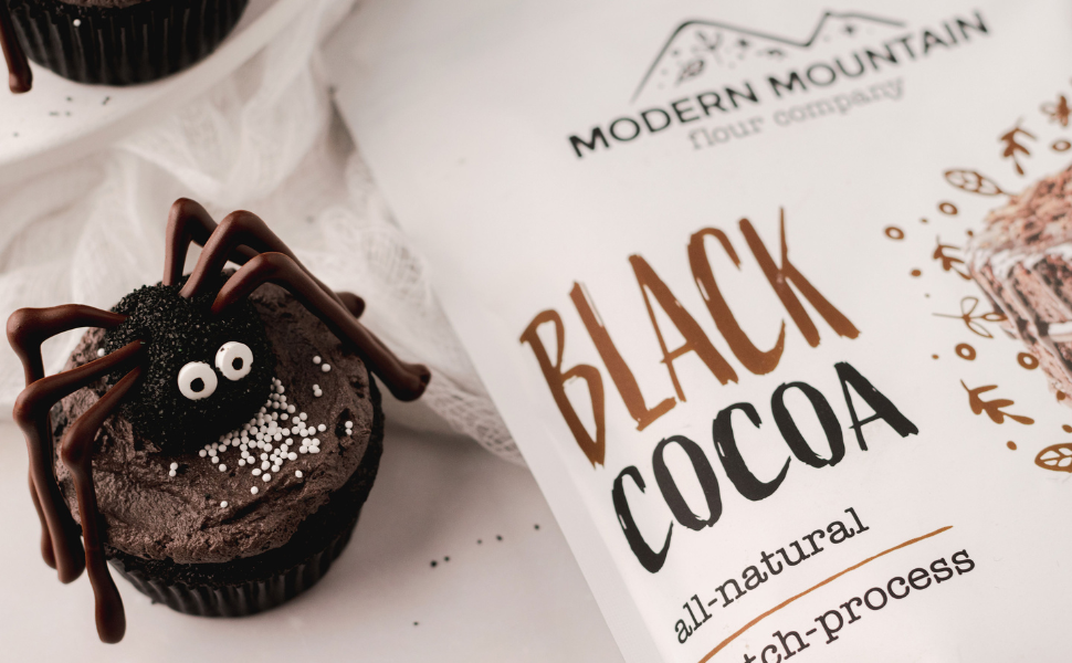 A pouch of Modern Mountain black cocoa powder next to a Halloween black cocoa spider cupcake