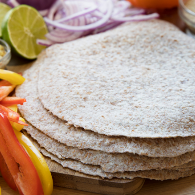 A stack of KAMUT flour tortillas next to various vegetables
