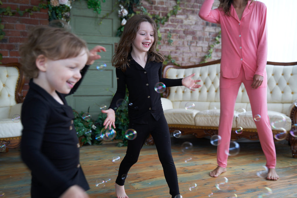 Kids in black Weekend Made pajama sets dancing with bubbles.