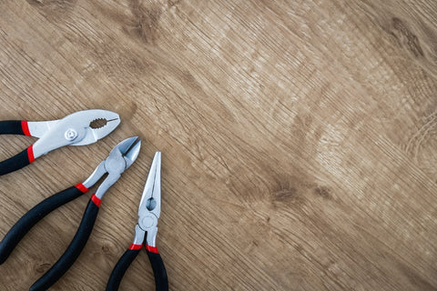 different pairs of pliers on a wooden table