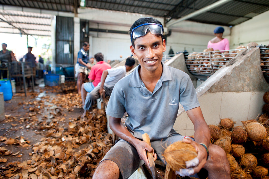 A smiling worker preparing coconuts for production.