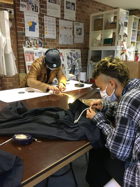 Two people in a studio sewing clothing.