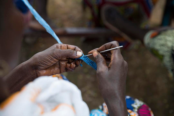 close up image of Gambian artisan hands crocheting 'plarn' plastic waste yarn