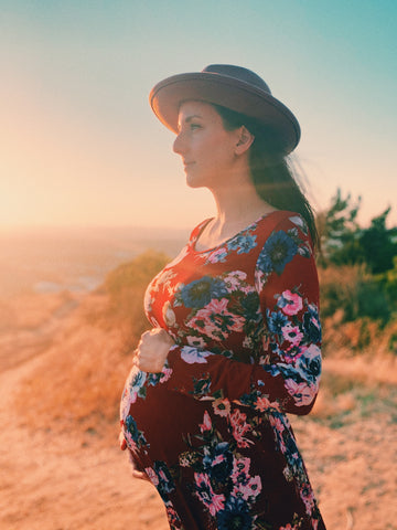 Becky holding her pregnant bump in a scenic sunset