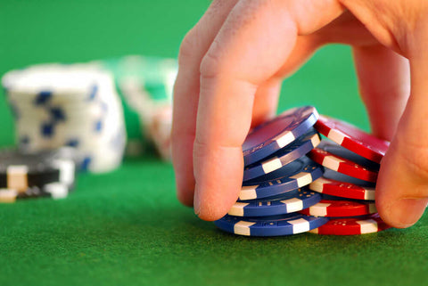Close up image of a person performing a poker chip shuffle on a felt poker table