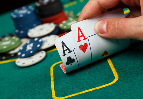 A poker player looks at their hole cards, seeing two aces.