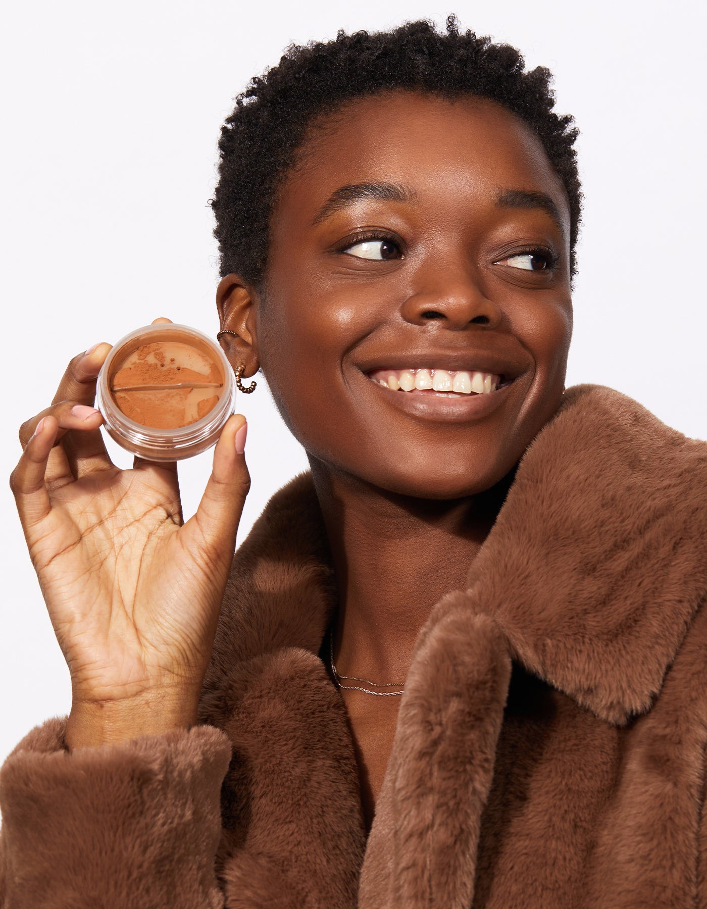 A woman holding Tinted Face Powder by Jones Road