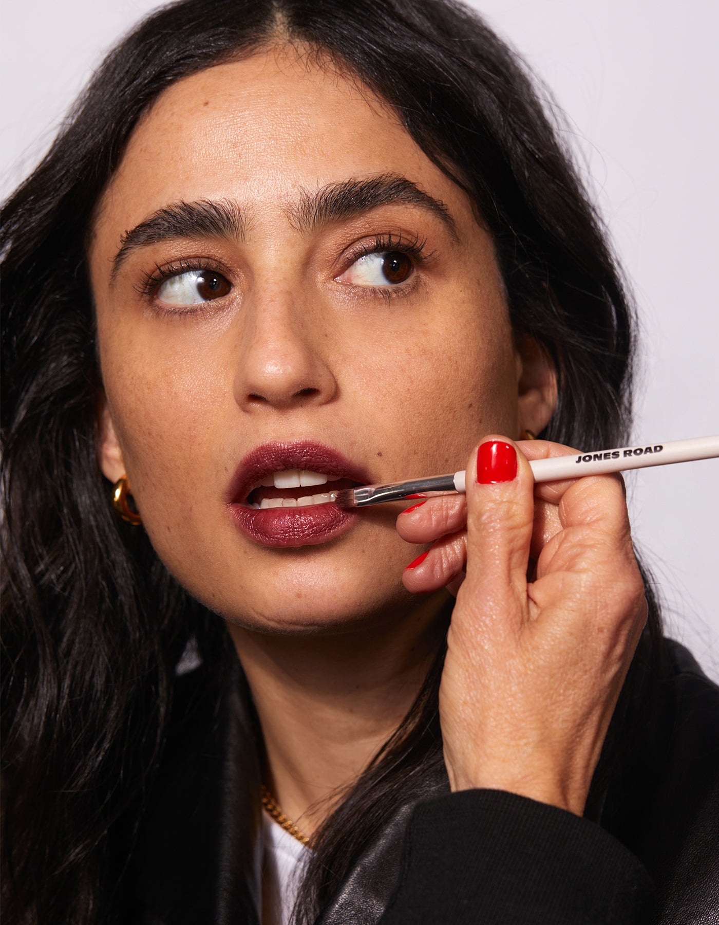 A woman applying Jones Road Beauty lip tint on her lips.