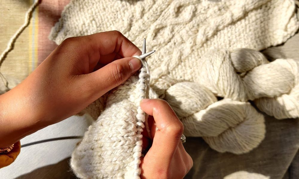 This image shows a person knitting a sweater with a needle. Get inspired to create your own cozy knitwear!