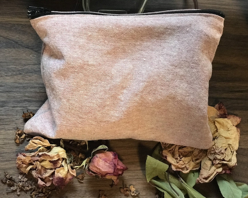 Image of a pink linen bag and some of the dried herbs it contains, including rose petals, rose buds, rose leaves, and lilac flowers.