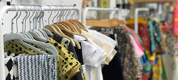 Cute patterned children's clothes lined up on hangers, in the Bristol Pop-Up Shop