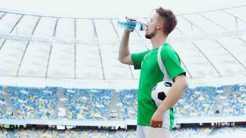 Soccer player drinking water as a part of his soccer diet.