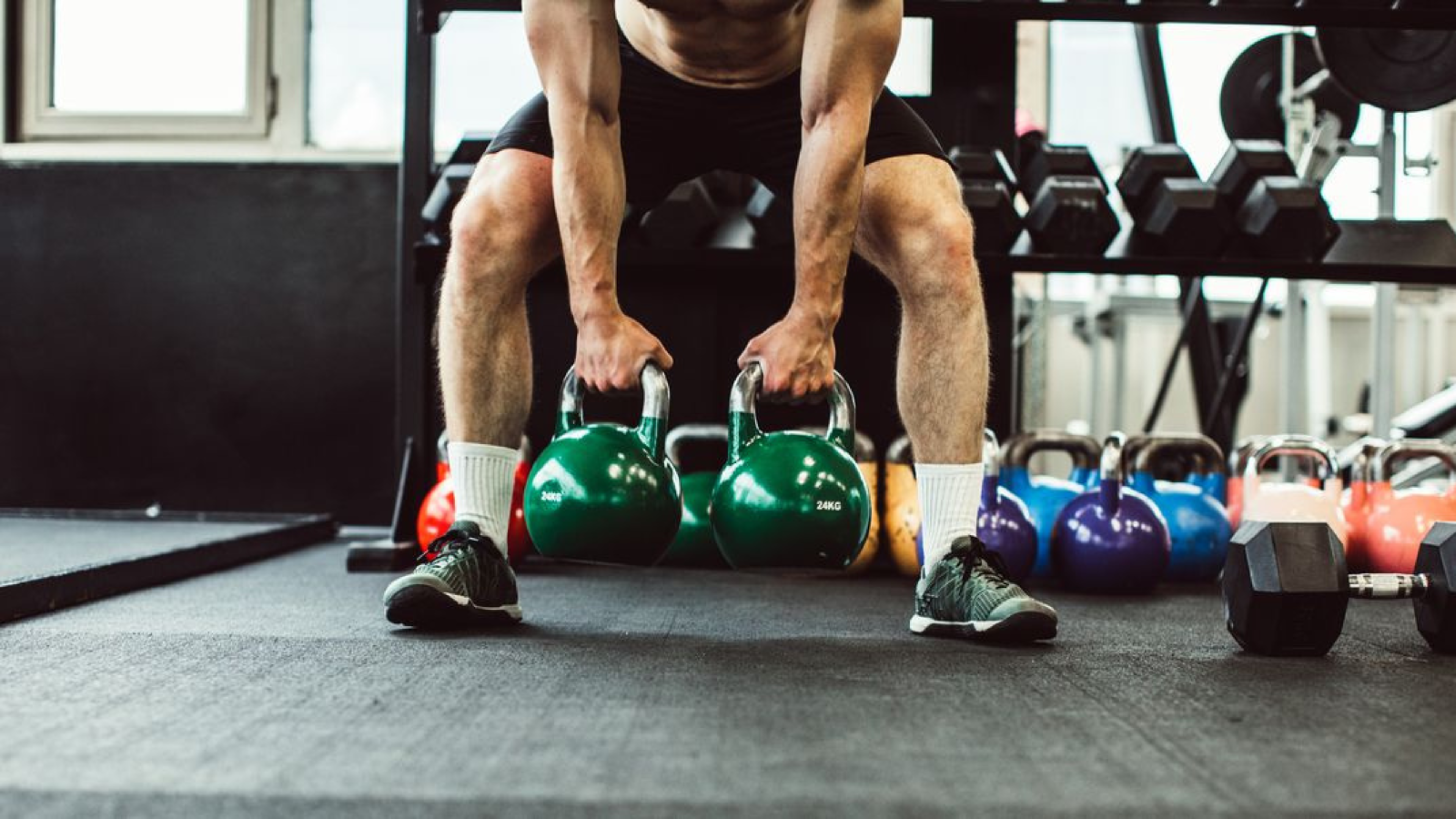 Homem realizando levantamento terra com kettlebells