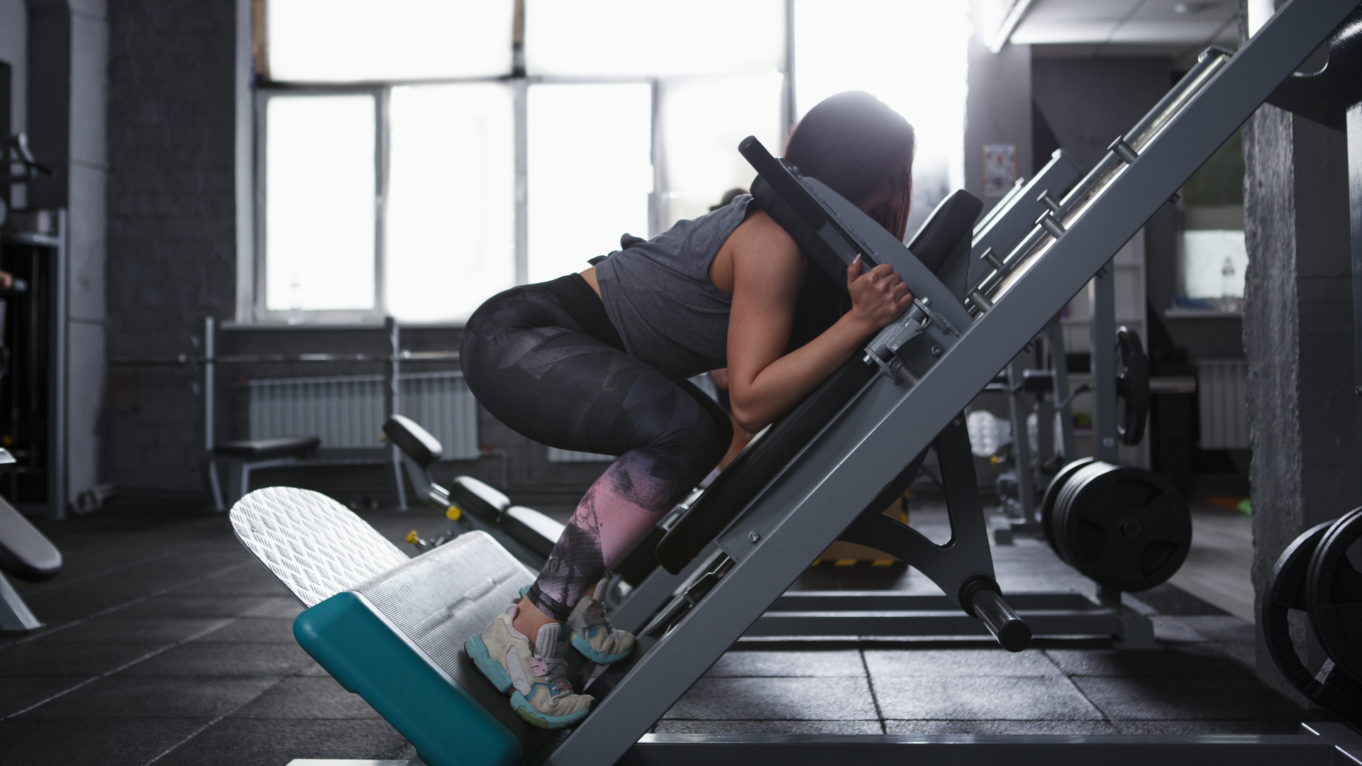 Mulher usando leg press invertido ou hack