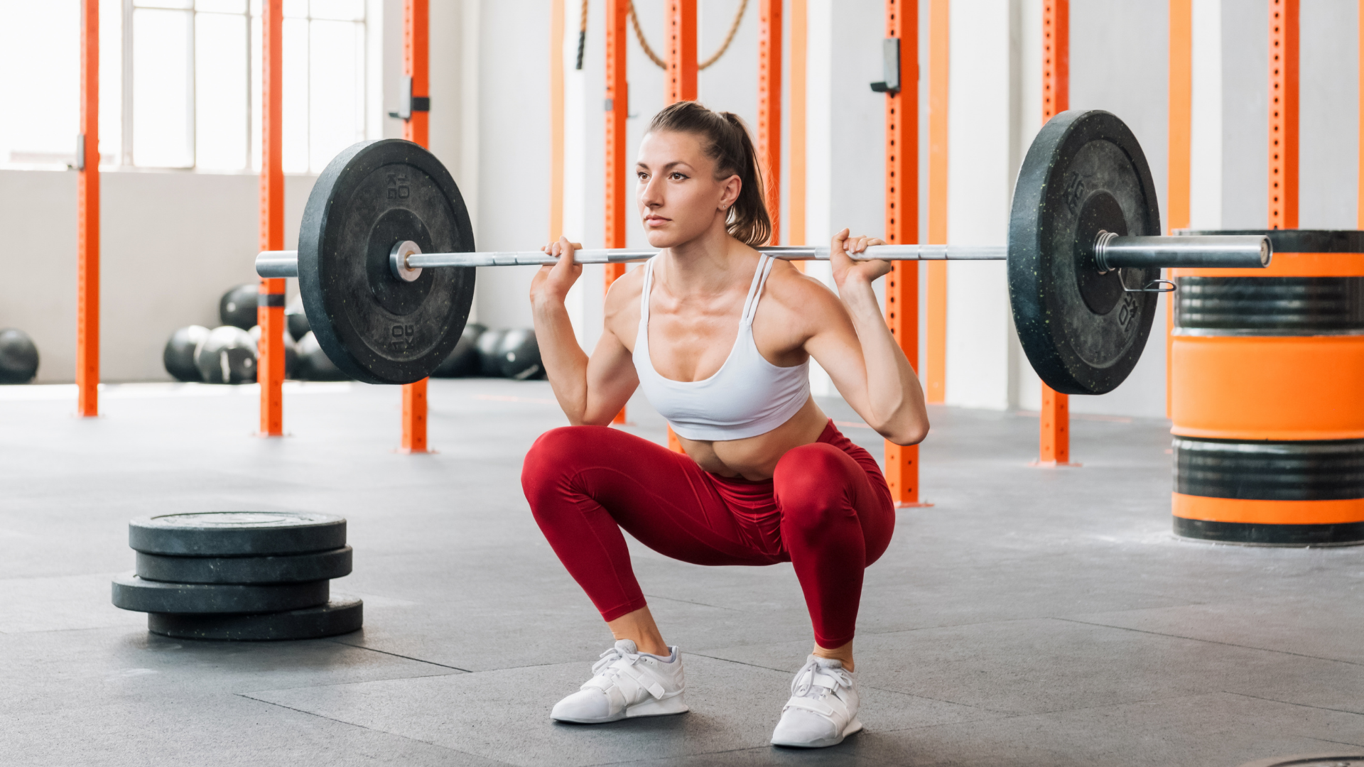 Mulher realizando exercício de agachamento com barra olímpica