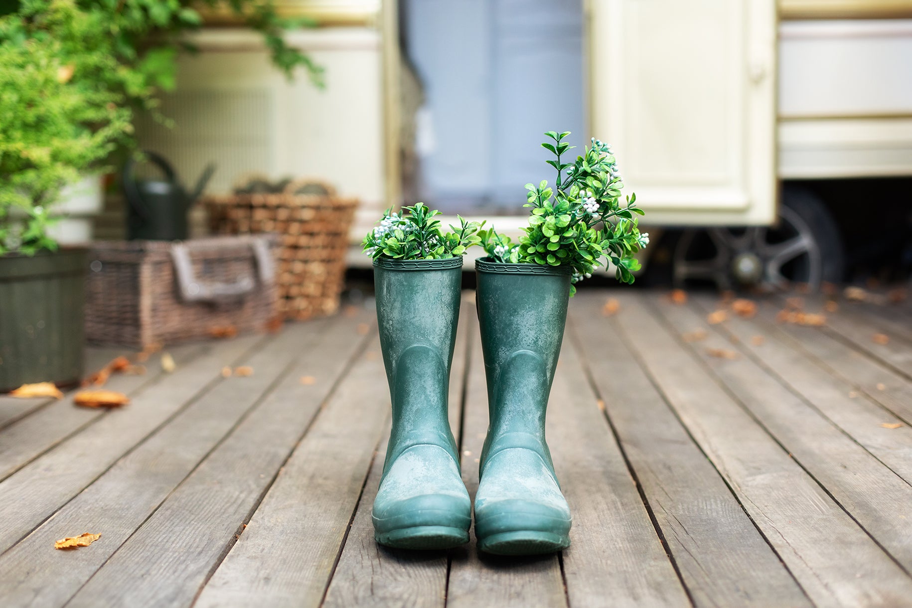 Back porch with a pair of green rainboots with plants in them.