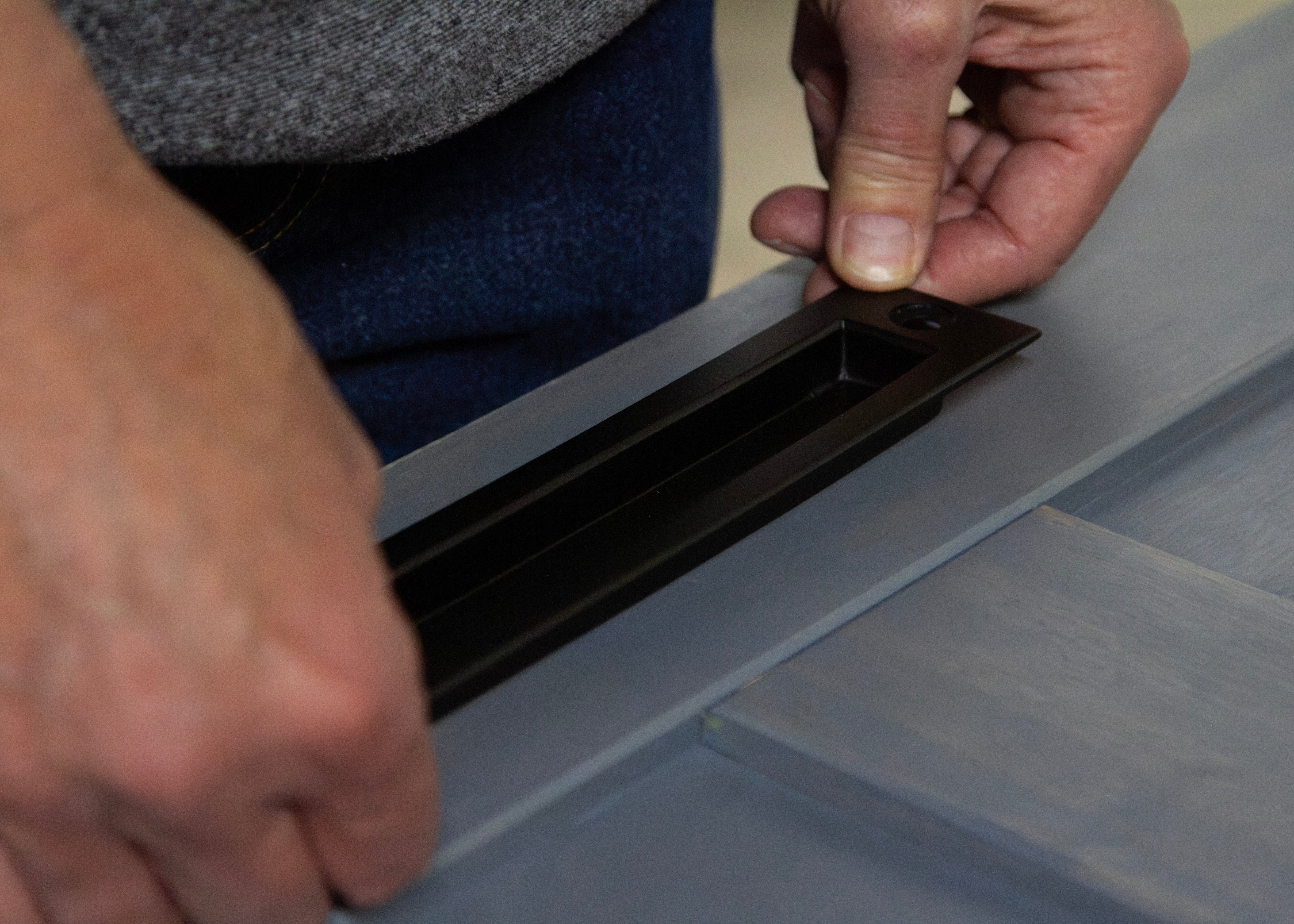 Man's hands installing barn door handle for interior door.