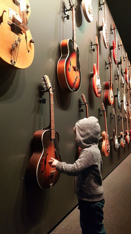 Young boy touching a Maton guitar Powerhouse Museum