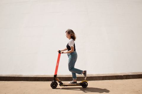 A young woman riding an electric scooter own the street.