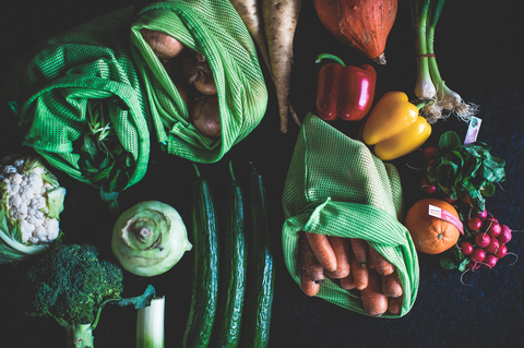 Vegetables and other produce on a table and in reusable produce bags. 