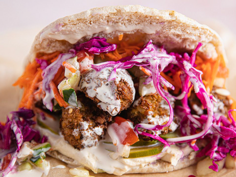 A photo of a falafel sandwich with purple cabbage and a creamy dressing. 