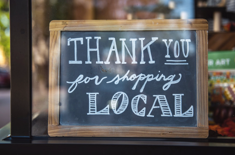 A sign in a shop window that reads “Thank You For Shopping Local”